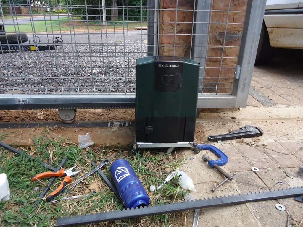 Sliding gate motor installed beside a gate rack during installation   